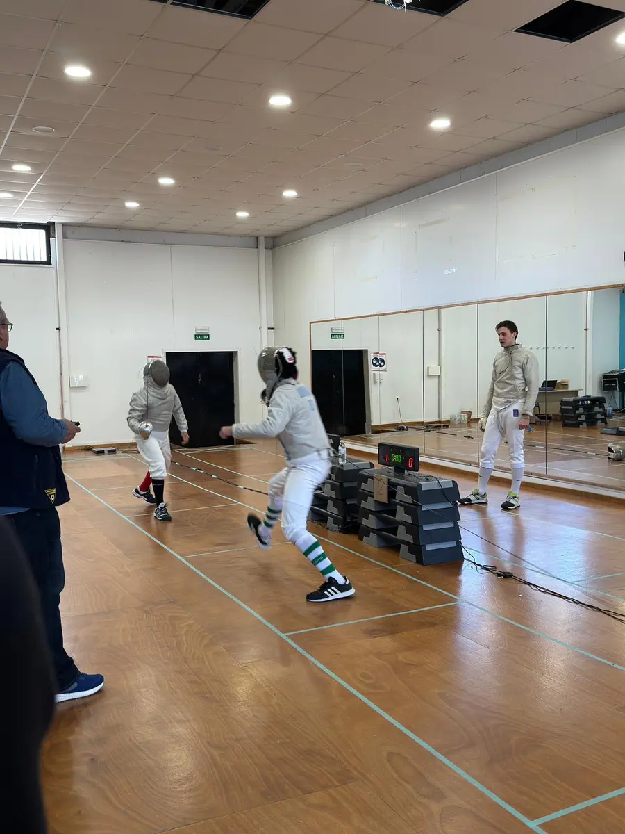 Dos esgrimistas en un asalto de entrenamiento en una sala con espejos