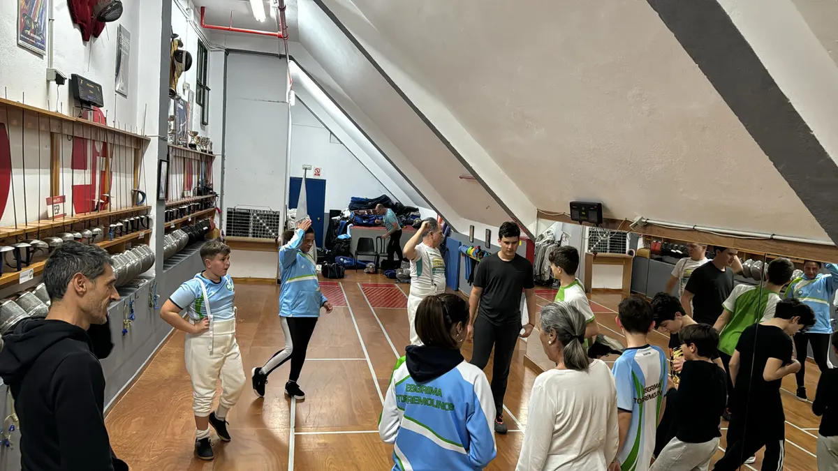 Clase grupal de esgrima en la sala del club, con deportistas de distintas edades
