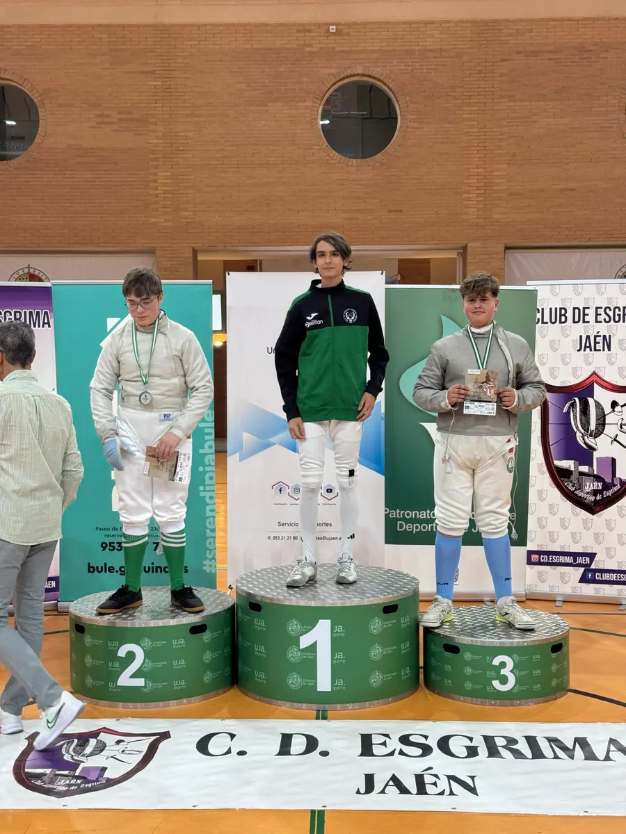 Tres jóvenes esgrimistas con medallas en un podio de torneo en Jaén