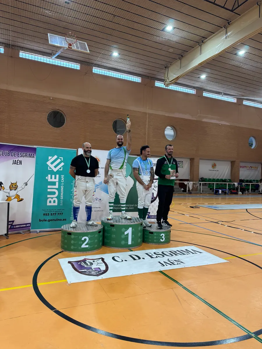 Podio con cuatro esgrimistas veteranos, el ganador levantando un trofeo, en un torneo en Jaén