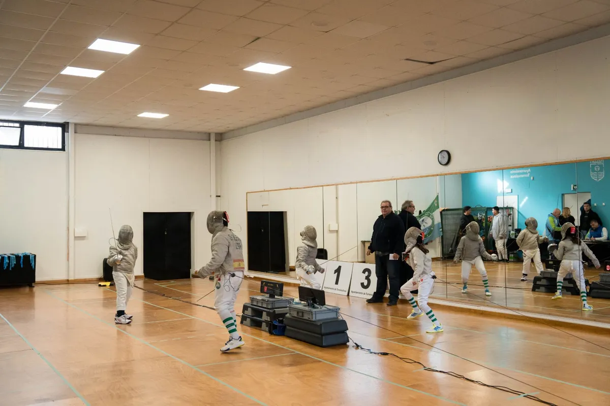 Vista general de una sala municipal de deportes de Torremolinos con varias pistas de esgrima, marcadores y espejos durante el Torneo de Navidad